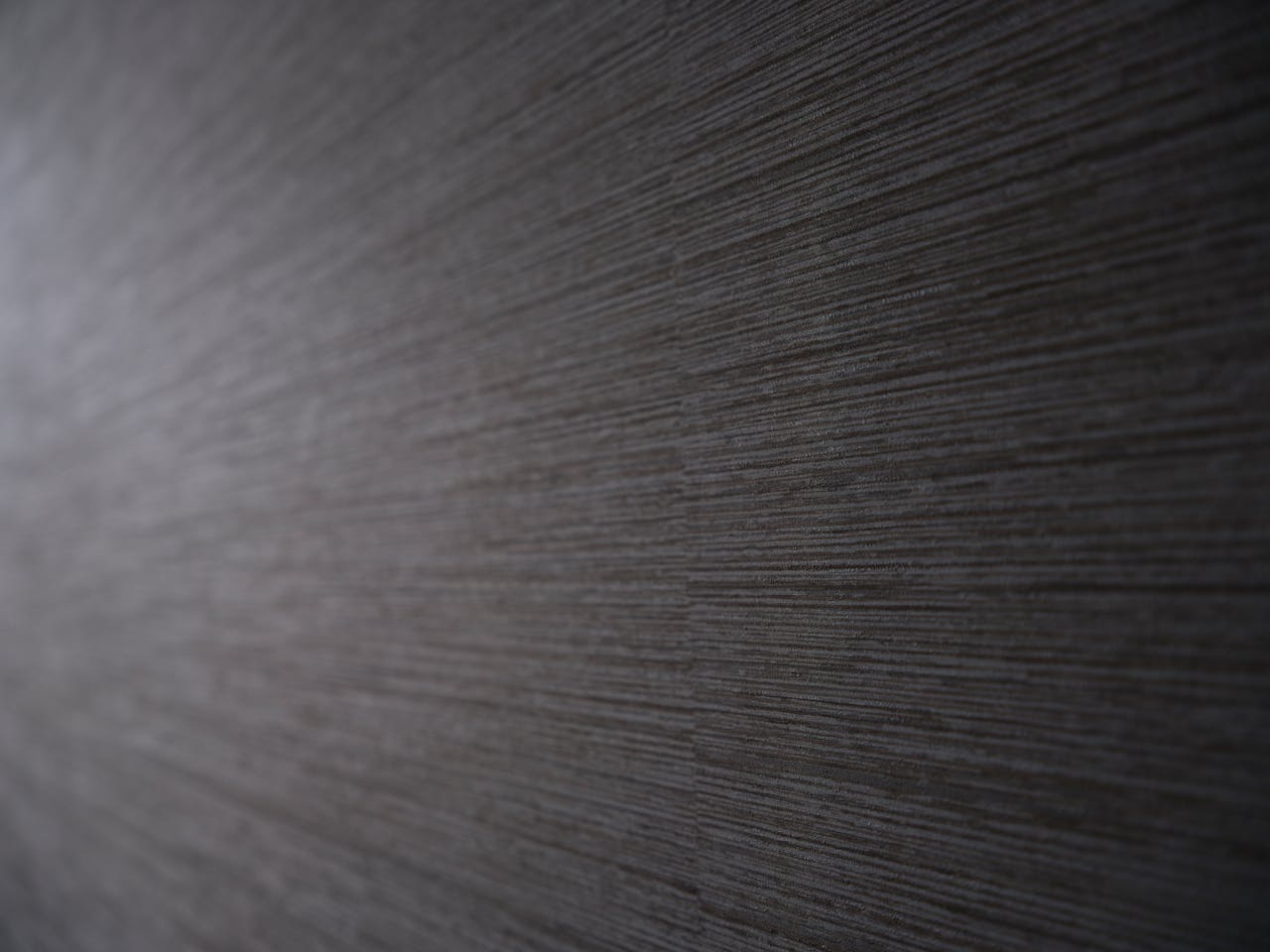 Close-up of textured gray wallpaper featuring subtle horizontal lines creating a modern pattern.