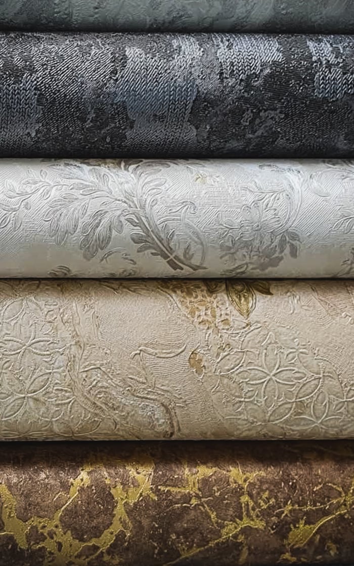 ours-journey A close-up view of ornate, embossed fabric rolls in various colors and textures.